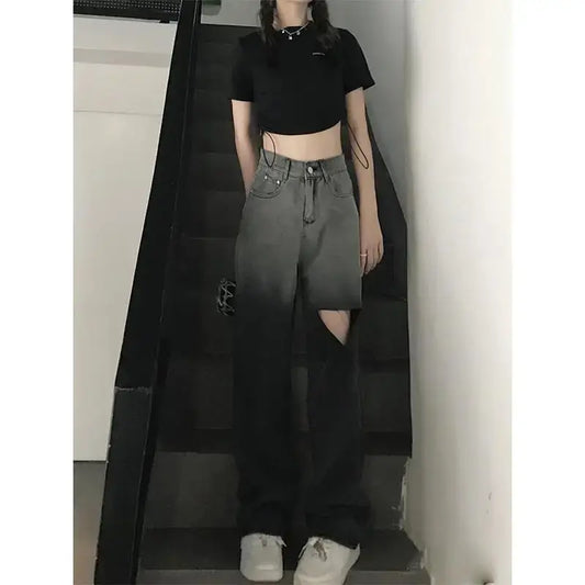 High waist ripped jeans for women shown on a model wearing a black crop top and sneakers, standing on stairs.