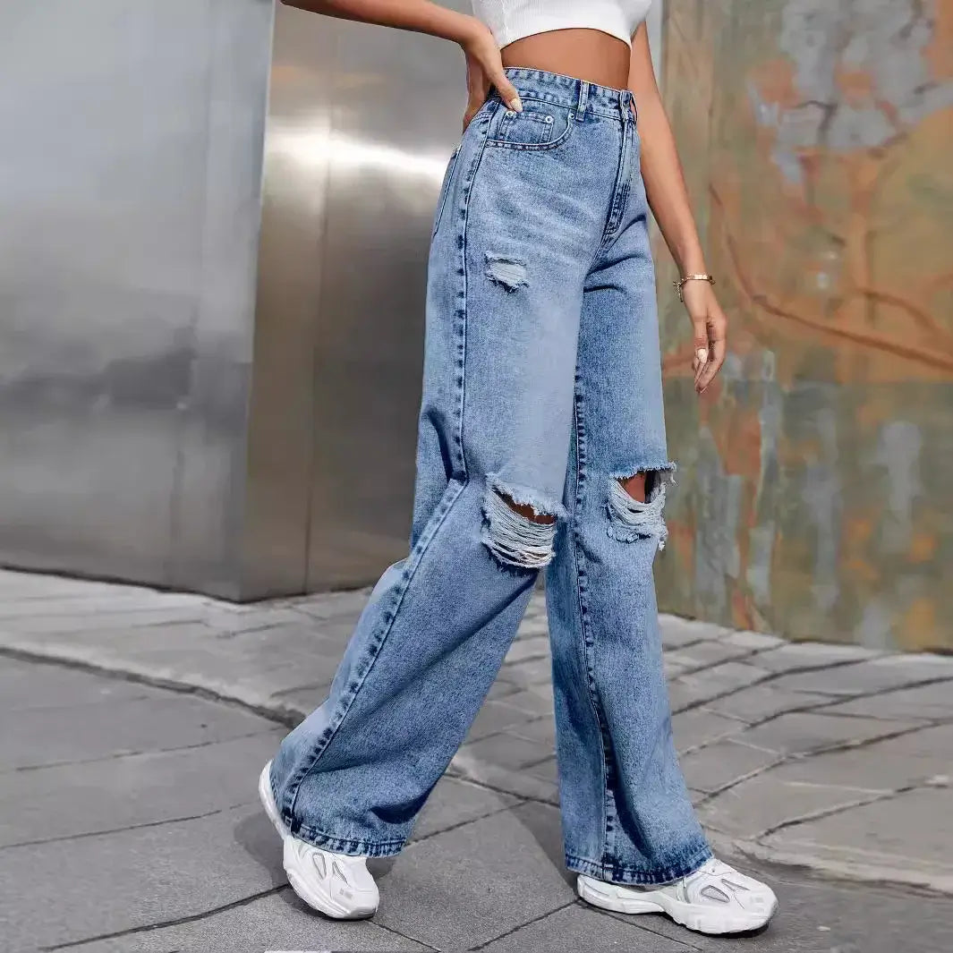 Model wearing ripped high waist wide leg jeans in light blue with distressed details, styled for a casual look.